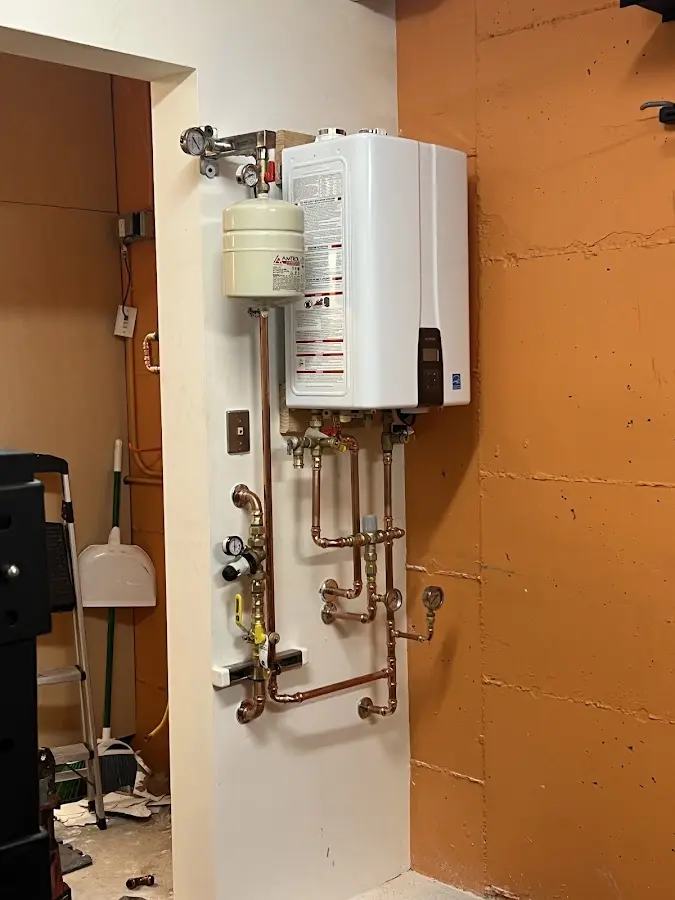 Plumbing technician inspecting water heater connections in Topsham
